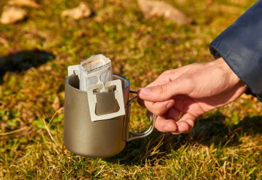 Sonbahar dağlarında bir fincan taşınabilir damlalı kahve hazırlanıyor. Vahşi doğanın arka planına karşı