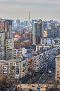 Ukrayna 'nın Kyiv kentindeki yoğun kentsel manzaranın yüksek açılı görüntüsü, hafif bulutlu bir gökyüzü altında çeşitli çok katlı binalar ve mimari tarzlar gösteriyor..
