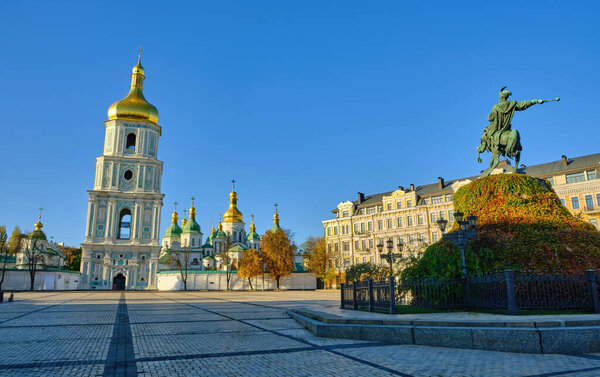 A sunny autumn day on Sophia Square in Kyiv, Ukraine, featuring the historic Saint Sophia's Cathedral with its golden-domed bell tower and the monument to Bohdan Khmelnytsky.