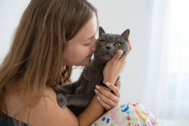 Genç bir kadın İngiliz steyşın kedisine burnuyla dokunuyor.