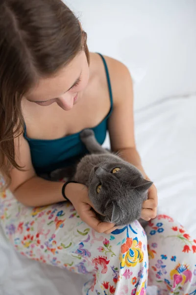 stock image Young woman gently holding her British shorthair cat in her bed