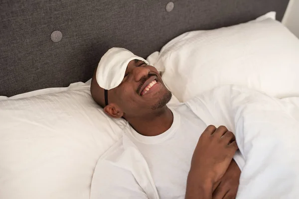Junger Schwarzer Afrikaner Mit Augenbinde Der Lachend Einem Bett Liegt Stockbild