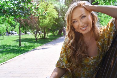 Halka açık bir parkta rahatlayan mutlu sarışın kadın.