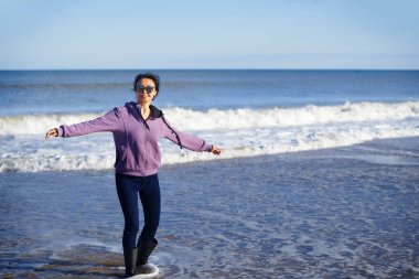 Okyanusun kenarında eğlenen bir kadın.