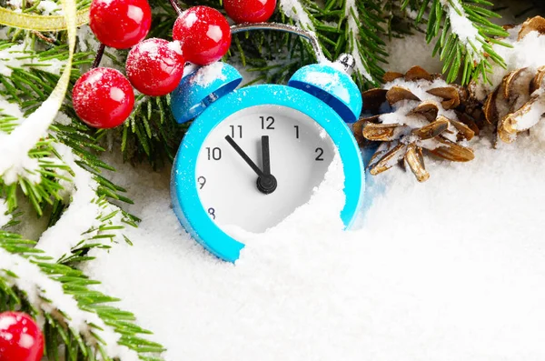 Christmas background of spruce branches with pine cones berries and alarm clock