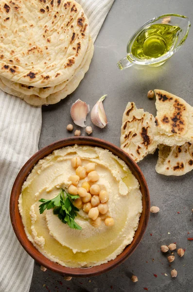 Flat lay view at hummus topped with chickpeas and green coriander leaves on stone table served with traditional Pita bread