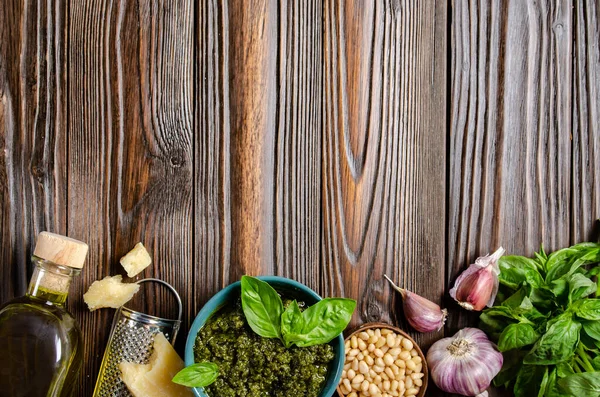 Flat lay food background of genovese pesto sauce and its ingredients on wooden kitchen table with copy-space