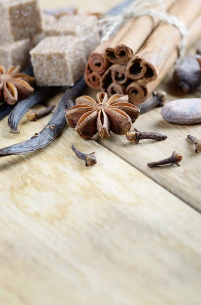 Vanilla, cinnamon, cocoa, anise and cloves on wooden table with copy-space