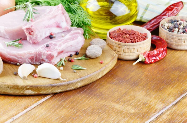 Raw pork rib chops on cut board with rosemary, chili pepper garlic and oil