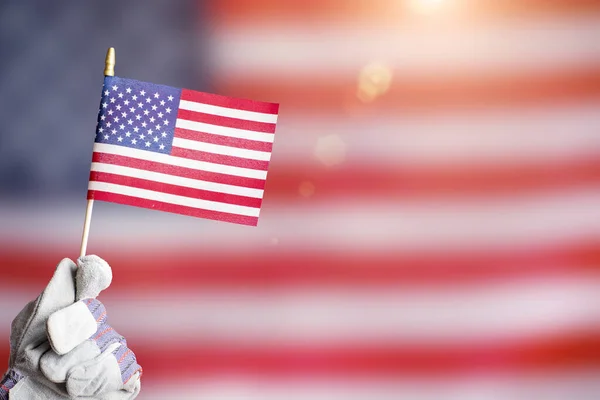 Hand in protective glove holding us flag labor day background