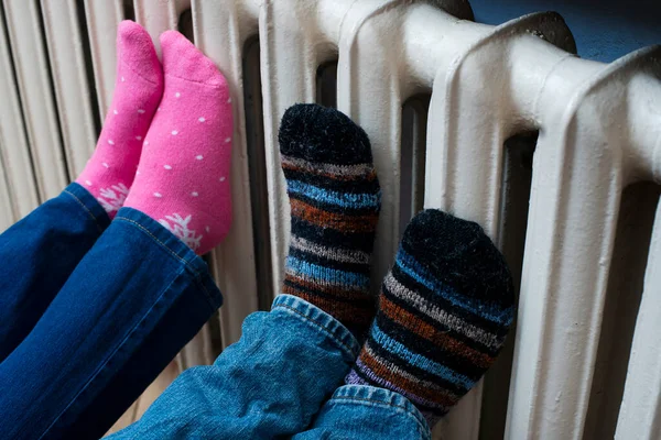 Couple warming up their feet on central heating radiator.