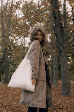 Sonbaharda parkta neşeli bir kızın portresi. Dışarıda palto giyen mutlu kız. Ilık sonbahar ve açık havada yürüyüş kavramı.