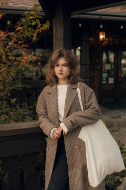 Sonbaharda parkta neşeli bir kızın portresi. Dışarıda palto giyen mutlu kız. Ilık sonbahar ve açık havada yürüyüş kavramı.