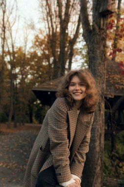 Sonbaharda parkta neşeli bir kızın portresi. Dışarıda palto giyen mutlu kız. Ilık sonbahar ve açık havada yürüyüş kavramı.