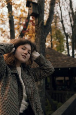 Sonbaharda parkta neşeli bir kızın portresi. Dışarıda palto giyen mutlu kız. Ilık sonbahar ve açık havada yürüyüş kavramı.