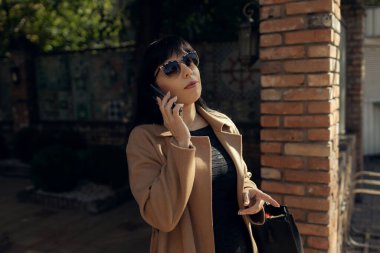 Orta yaşlı bir iş kadını dışarıda şık bir düşüş yaşıyor. Kadın stili model şehir caddesinde yürüyor. Sonbahar trendi, moda kıyafeti