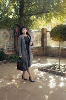 Orta yaşlı bir iş kadını dışarıda şık bir düşüş yaşıyor. Kadın stili model şehir caddesinde yürüyor. Sonbahar trendi, moda kıyafeti