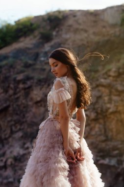 Kayalardan oluşan bir arka planda Boho tarzı elbise giyen modaya uygun genç bir manken. Kadın güzelliği ve tarz kavramı. Reklam ya da kıyafet satışı tasarımı.