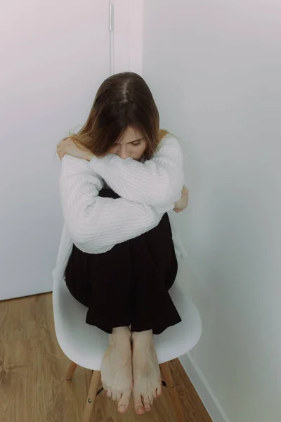 A young girl immersed in her thoughts sits on a chair on a white background, space for text. The concept of self-knowledge. Visual content for psychotherapists and coaches