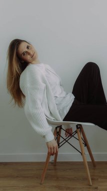 A young girl immersed in her thoughts sits on a chair on a white background, space for text. The concept of self-knowledge. Visual content for psychotherapists and coaches