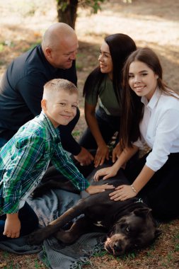 Labrador Retriever köpeğiyle parkta oynayan mutlu bir aile. Evcil hayvanlara sevgi ve sevgi, arkadaşlık arkadaşı. Köpek cins - Cane Corso