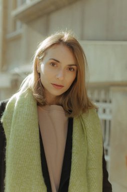 Parkta yüzünde mutlu bir gülümseme, sevinç dolu bir kadın, kameraya bakıyor. Şehir parkının bulanık arka planında yarı sezon kıyafetleri giymiş bir kız.