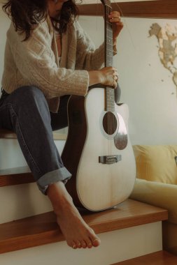 Yaratıcı hobi. Yetenekli genç bayan müzisyen koltuğunda tek başına oturup klasik gitar kullanarak enstrümantal bir şarkı besteler. Gülümseyen bayan müzik aletinde sakin bir melodi çalar. Boşluğu kopyala