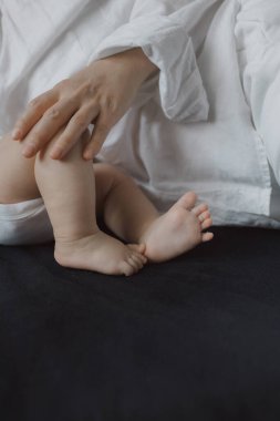 Annenin elleri yeni doğmuş bir bebeğin bacaklarını okşuyor. Mutlu annelik ve yeni doğan bakımı kavramı