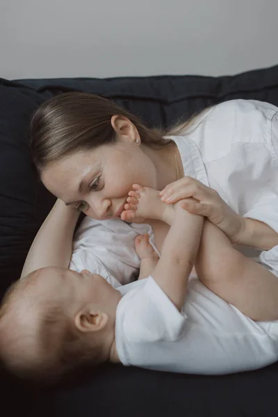 一个年轻女人和她的小宝宝在床上玩耍的侧视图 快乐孕产和新生儿护理的概念 — 图库照片