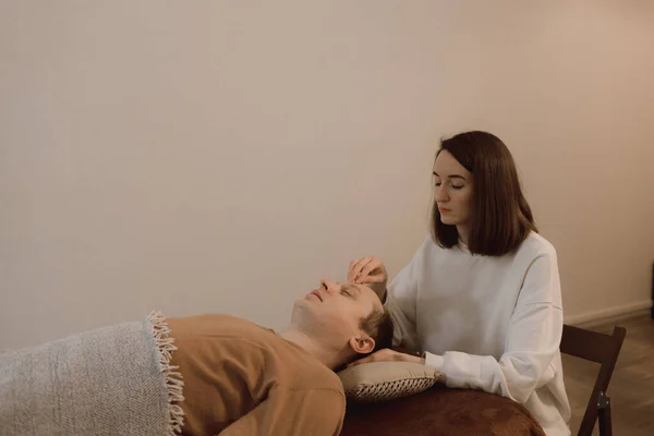 Energy massage for man relaxing and care treatment for body and mindfull health gentle woman arms holding head doing access bars and face young procedure. Energetic massage resumes the circulation of energy in body.