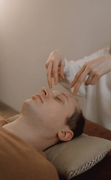 Энергетический массаж для мужчин расслабляющий и уход за телом и внимательное здоровье нежные руки женщины, держа голову, делая перекладины доступа и лицо молодой процедуры. Энергетический массаж возобновляет циркуляцию энергии в организме.
