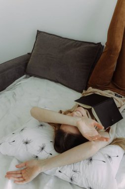 Yatak odasında not defteri olan zeki bir kız. Beyaz bir arkaplan ve mesaj için yeri var. Beyin fırtınası konsepti ve planlama, yatakta okumak, uzaktan eğitim