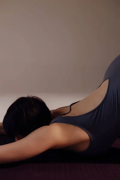 迷人的女人弯腰身体靠得很近 女运动员在演播室的垫子上伸展身体 一位强壮的 肌肉发达的女运动员以浅薄的背景从事体操运动 — 图库照片