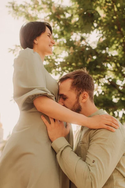 妊娠中のカップルは自然の中で抱擁 妊娠中の妻と一緒に公園を歩いている夫 幸せな家族のコンセプト写真 焦点がぼけてノイズ効果がない — ストック写真