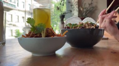 Sokak yemeği. Tabakta büyük bir porsiyon Tayland eriştesi. Yakın plan bir kadın, Tayland 'daki bir kafedeki tabaktan Asya eriştesi almak için çubuk kullanıyor..