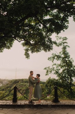 Hamile çift doğada sarılıyor. Parkta yürüyen hamile karısı olan bir koca. Mutlu aile konsepti fotoğrafı. Odak bulanıklığı ve gürültü efekti yok