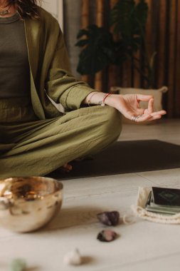 Kadın yoga minderinde otururken Tibet şarkı kasesinde oynuyor. Antika tonlu. Yumuşak odak bulanık ve gürültü efekti.