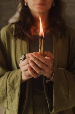 Genç bir kadın elinde sigara tiryakisi bir santo sopası tutuyor. Budist iyileştirme uygulamaları. Alanı negatif enerjiden arındırmak. Aromaterapi. Seçici odaklanma, kapat. Yumuşak odak ve gürültü etkisi.