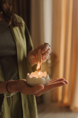 Genç bir kadın elinde sigara içen bir Palo Santo sopası tutuyor. Budist şifa uygulamaları. Boşluğu negatif enerjiden temizliyorum. Aromaterapi. Seçici odaklanma, kapat. Yumuşak odak ve gürültü etkisi.