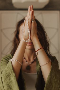 Kadının elinde doğal taşlardan yapılmış mücevherler var. Elleri yüzük ve bileziklerle süslenmiş. El sanatları ve yaratıcılık. Maneviyat, din, Tanrı kavramı..