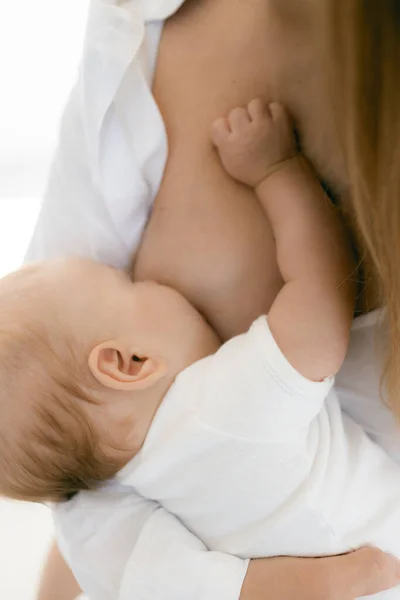 年轻的母亲抱着孩子 妇女在白色背景下喂哺新生婴儿 母亲和哺乳快乐的概念 闪烁着阳光 聚光柔和 过度曝光的照片 — 图库照片