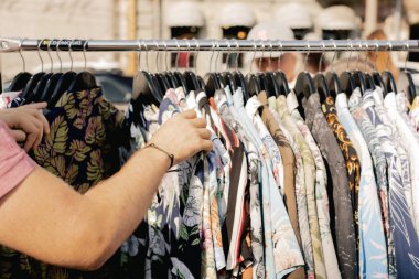 Perakende mağazasında farklı renklerde moda kıyafetleri seçiyor. Dışarıda eski giysiler olan bit pazarı. Geri Dönüşüm Konseptini Azalt.