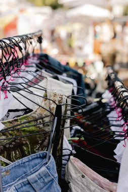 Perakende mağazasında farklı renklerde moda kıyafetleri seçiyor. Dışarıda eski giysiler olan bit pazarı. Geri Dönüşüm Konseptini Azalt.