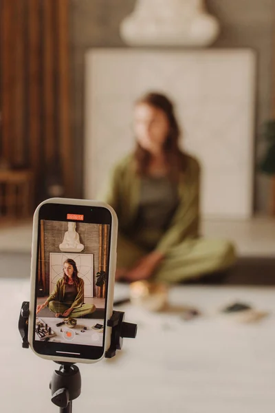 Live streaming on a smartphone - online yoga lesson. Vertical photo. Focus on smartphone.