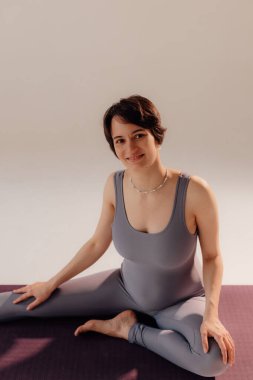 Genç hamile kadın yoga egzersizleri yapıyor ve stüdyoda meditasyon yapıyor. Sağlık, farkındalık, rahatlama ve sağIık kavramı.