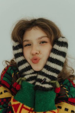 Örgü süveter ve sıcak eldivenlerle gülümseyen neşeli genç kız. Neşeli gülümseyen genç bir kadın Noel tatiline hazırlanıyor. Seçici odak.