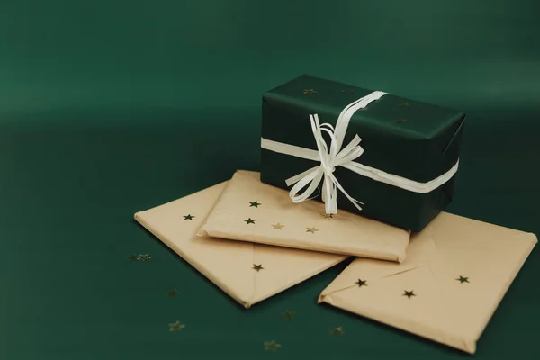 Festive gift and envelopes on green background. Minimalistic greeting cards and envelopes. Christmas and New Year.