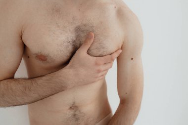 People, healthcare and problem concept - man suffering from back pain or reins. Close up hands touching back pain. Man standing on white background. No focus blurred and noise effect.