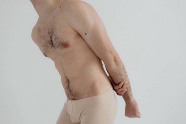 People, healthcare and problem concept - man suffering from back pain or reins. Close up hands touching back pain. Man standing on white background. No focus blurred and noise effect.