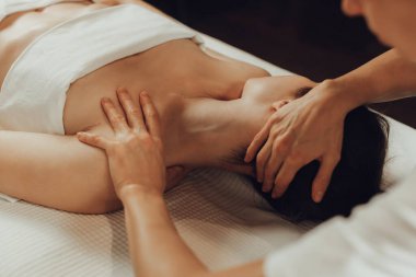 Masaj masasında yatan genç bir kadının omuzlarına masaj yapan kadın masörlerin elleri. Fizik tedavi konsepti, boyun basınç noktası..